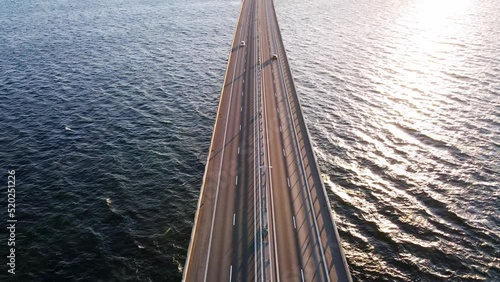 Drone flying over an Oresund bridge at the sunset in summer. Cinematic shot of long tunnel bridge between Sweden and Denmark. Cars driving on a huge bridge shot from the top. High quality 4k footage