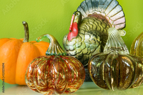 A mantle display for Thanksgiving with glass blown pumpkins and a turkey candle.