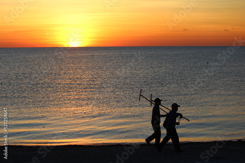 sunset on the beach with workers walking by
