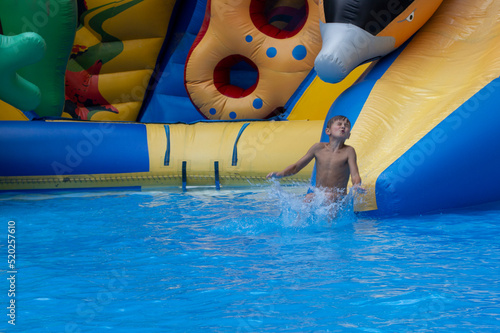 Boy has into pool after going down water slide during summer. little boy sliding down water slide and having fun