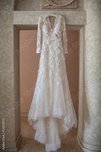 Wedding dress hanging on the door arch © tsezarina