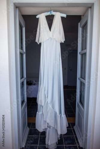 Wedding dress hanging on the door arch © tsezarina