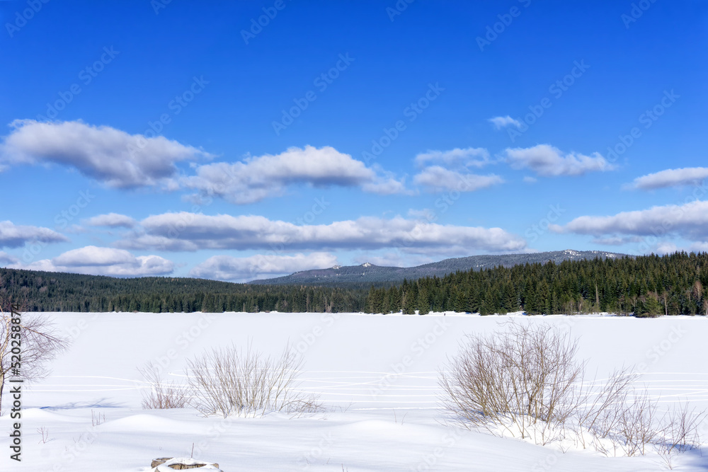 Frozen water reservoir on the Czarna Nisa river by the dam in Bedrrichov, Czech Republic, Europe. In the background you can see the peaks of the Izera Mountains. Frozen water reservoir on the Czarna Nisa river by the dam in Bedrrichov, Czech Republic, Europe. In the background you can see the peaks of the Izera Mountains.