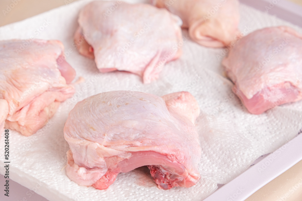 Chicken thighs are dried on a paper towel after washing for further freezing. Chicken thighs are dried on a paper towel after washing for further freezing.