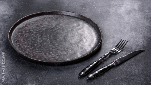 Black plate on a black background. Flat lay, top view, copy space