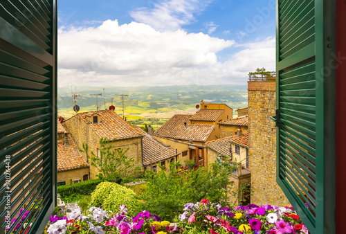 Canvas Print View through an open window with shutters over the medieval hill town of Volterra Italy, with the hills and countryside of Tuscany in the distance