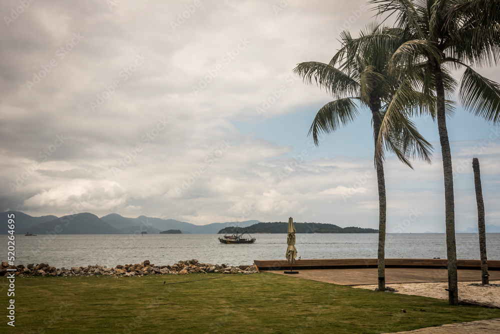 View of the sea, boat and palm tree at Angra dos Reis town, State of Rio de Janeiro, Brazil. Taken with Nikon D750 24-120 lens, at 40mm, 1/640 f 11.0 ISO 160. Date: Oct 23, 2019 View of the sea, boat and palm tree at Angra dos Reis town, State of Rio de Janeiro, Brazil. Taken with Nikon D750 24-120 lens, at 40mm, 1/640 f 11.0 ISO 160. Date: Oct 23, 2019