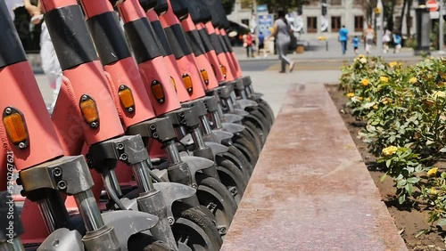 Many electric kicksharing scooters are lined up next to each other, ready to ride around the city. A modern popular way to get around the city is an electric scooter photo