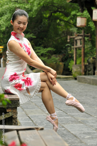 Chinese girl is showing ballet posture at the old buildings alley
