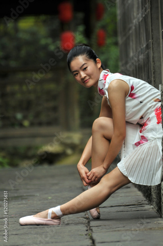 Chinese girl is showing ballet posture at the old buildings alley