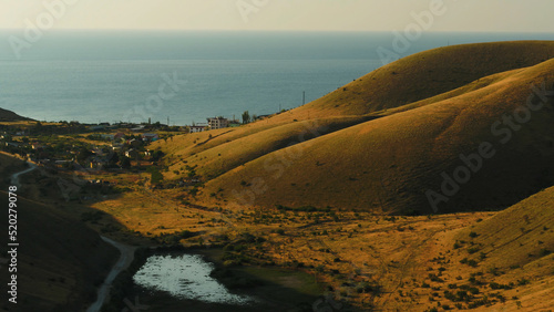 Fototapeta Naklejka Na Ścianę i Meble -  Top view of the village near the sea near the hills. Shot. Beautiful Sunny day in the village by the sea in autumn