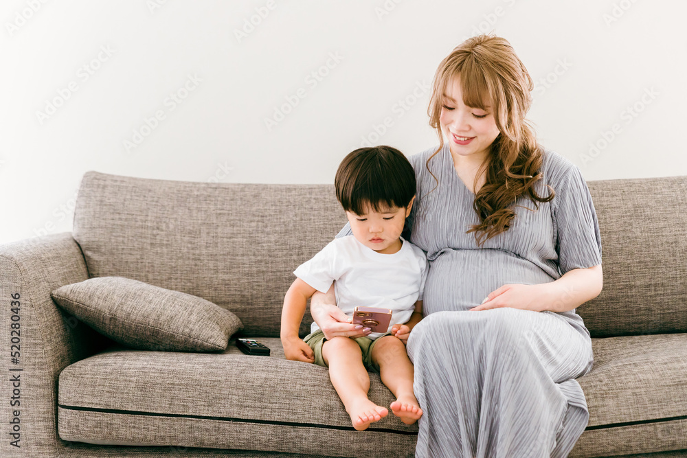 子供とスマホを見る妊娠中の日本人女性

