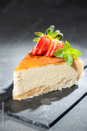 Homemade Traditional Cheesecake with fresh mint and sliced strawberries.