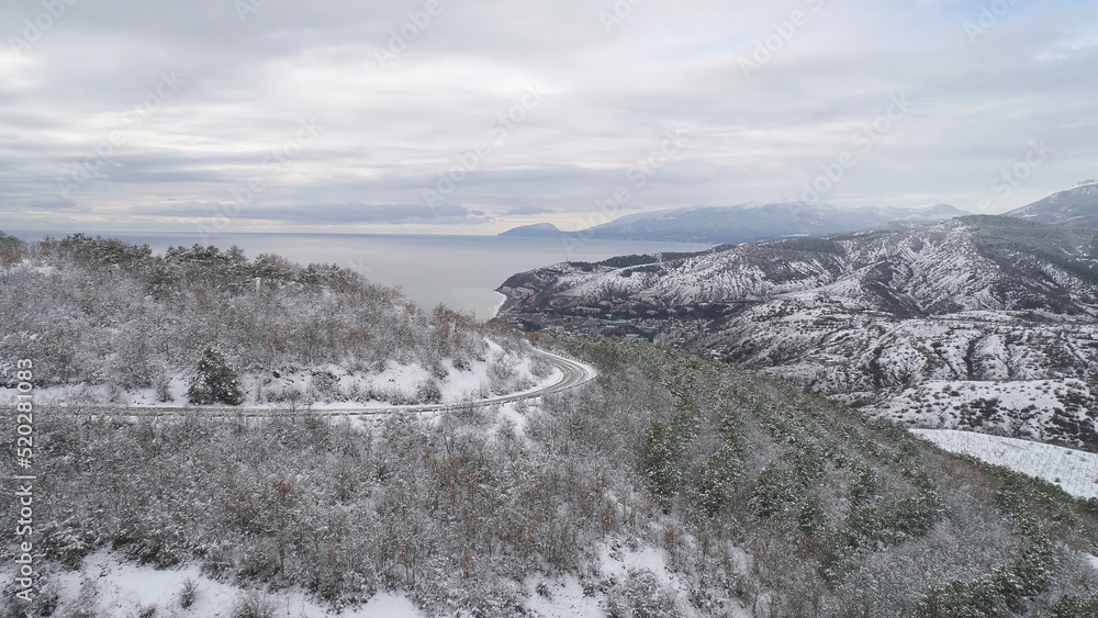 Top view of the city near the sea in winter. Shot. Snowy expanses in the mountainous area near the city