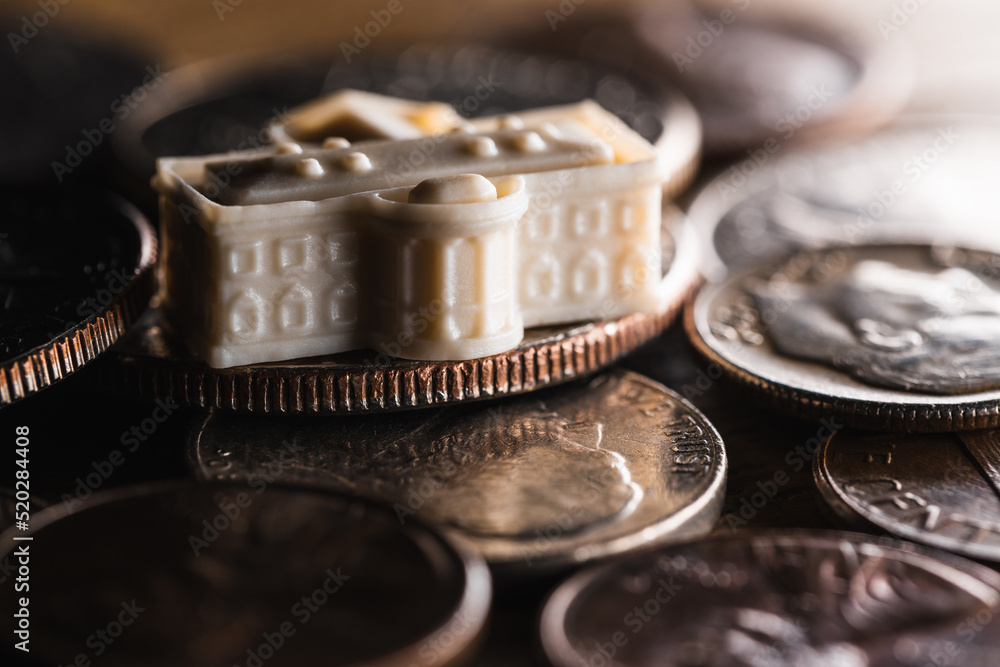 A miniature model of the White House in Washington D.C. sitting on some American coins money economy concept A miniature model of the White House in Washington D.C. sitting on some American coins money economy concept
