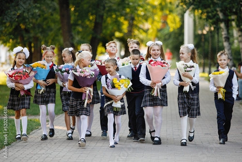 Girls and boys in school uniforms with flowers.
