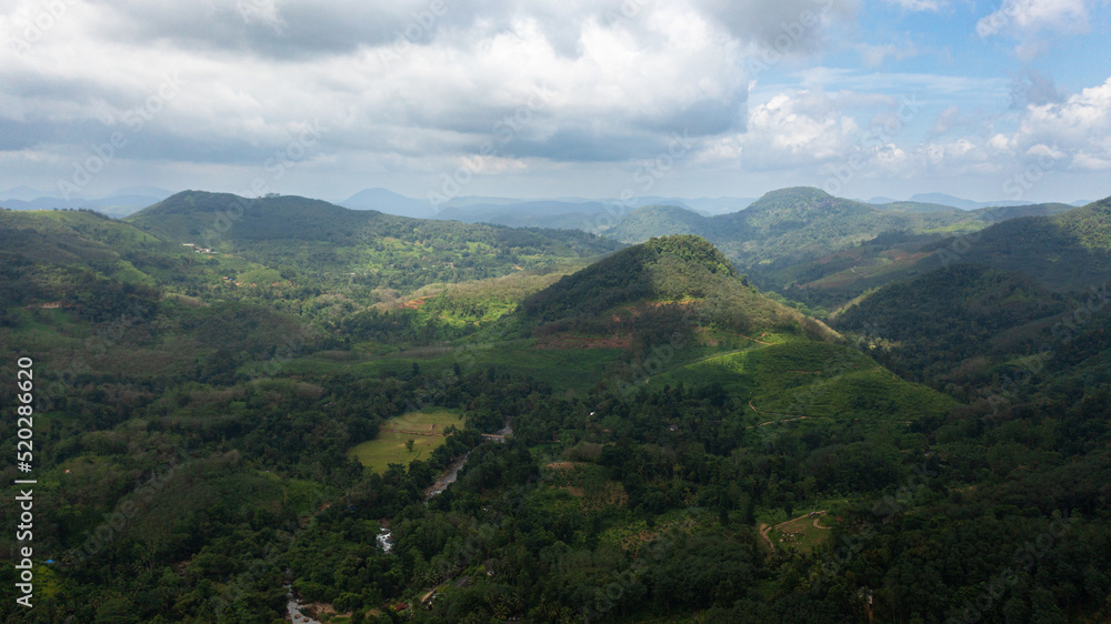 Top view of Mountains covered rainforest, trees and blue sky with clouds. Sri Lanka.