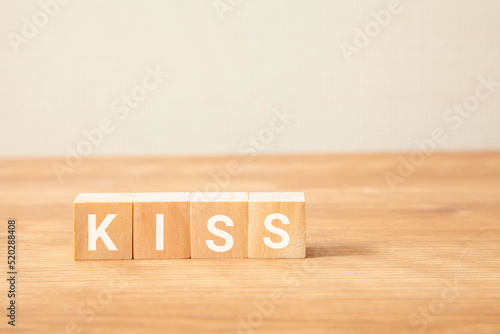 KISSの文字。キス。簡略化。Keep It Simple, Stupid。4つの木製ブロックに書かれている。白い背景。