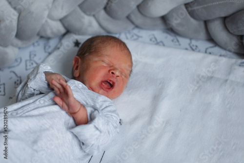 ewborn baby yawns on a blue blanket. photo