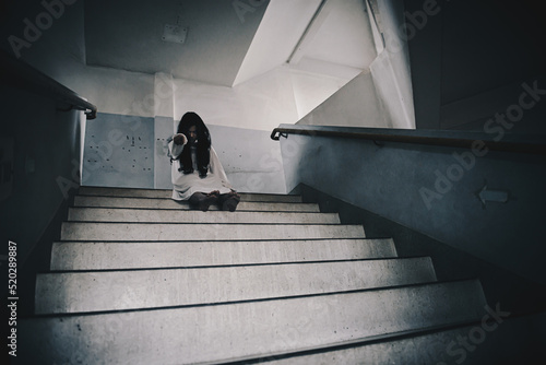 Horror woman ghost creepy zombie sitting on stair in haunted house