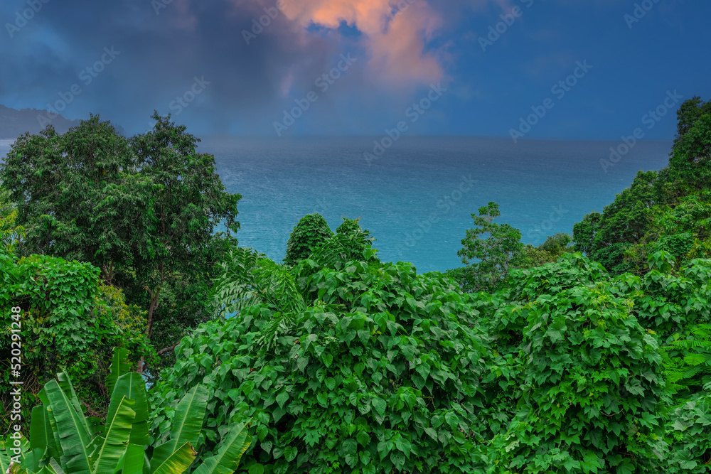 Fototapeta premium Colourful Skies Sunset over Head Laem Sing Beach in Phuket Thailand. This Lovely island waters are turquoise blue waters, lush green mountains colourful skies and beautiful views of Pa Tong Patong