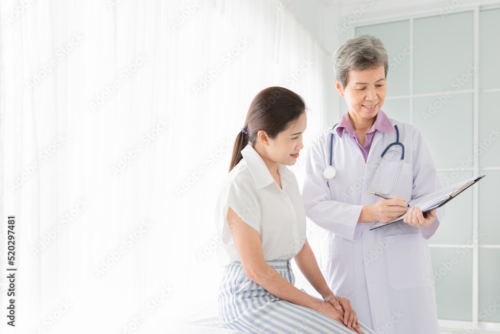 asian female doctor talk with patient in hospital, she screening and write patient information on patient chart, healthcare promotion asian female doctor talk with patient in hospital, she screening and write patient information on patient chart, healthcare promotion