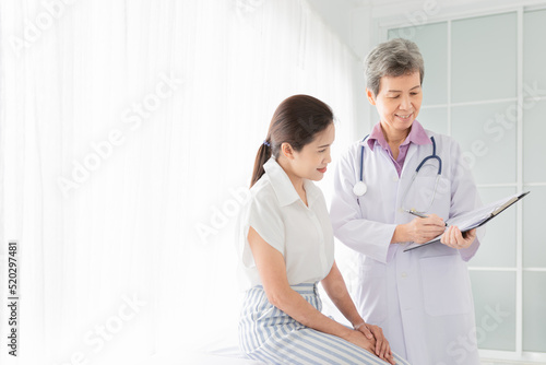 asian female doctor talk with patient in hospital, she screening and write patient information on patient chart, healthcare promotion