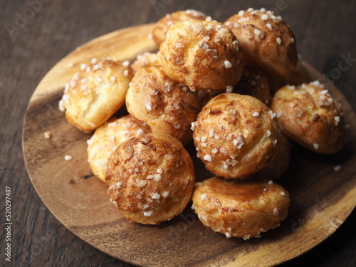 Foto small choux pastry coated with white pearl sugar on wooden plate