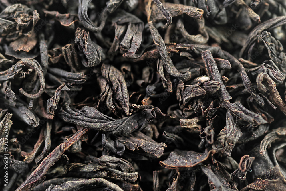 Premium black loose leaf tea as a background. Texture of dry black tea leaves. Extreme macro mode Premium black loose leaf tea as a background. Texture of dry black tea leaves. Extreme macro mode