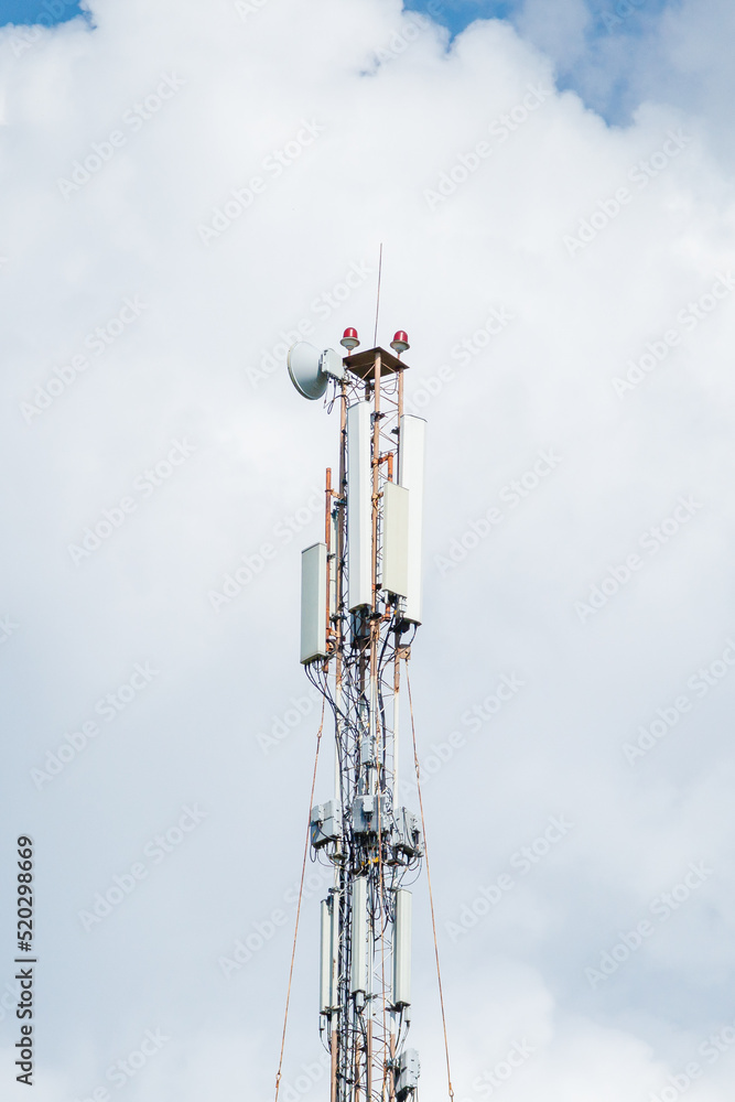 Telecommunication tower of 4G and 5G cellular. Macro Base Station. 5G radio network telecommunication equipment with radio modules and smart antennas mounted on a metal against cloulds sky background.