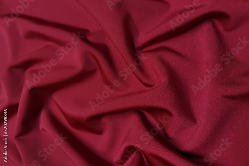 Red supplex crumpled or wavy fabric texture background. Abstract linen cloth soft waves. Silk fabric. Smooth elegant luxury cloth texture. Concept for banner or advertisement.