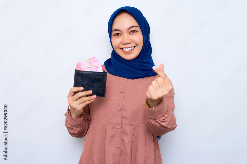 Smiling young Asian muslim woman in pink shirt holding wallet full of ...