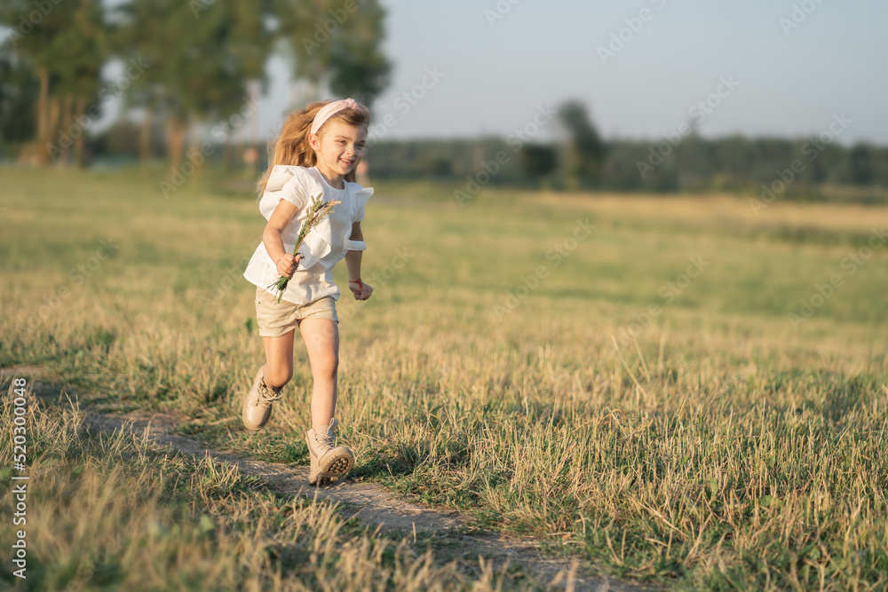 Happy childhood in the village. A child with long blonde hair runs across the field. Joyful children's games. Summer in the village at grandma's