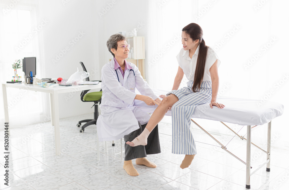 asian female doctor holding leg of patient in hospital, they training to rehab muscle in rehabilitation clinic asian female doctor holding leg of patient in hospital, they training to rehab muscle in rehabilitation clinic