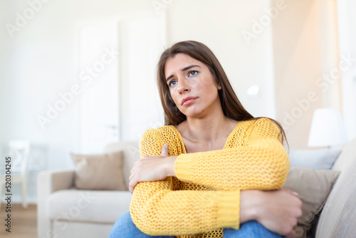 anxious worried woman sitting on couch at home. Frustrated confused female feels unhappy, problems in personal life, quarrel break up with boyfriend and unexpected pregnancy concept