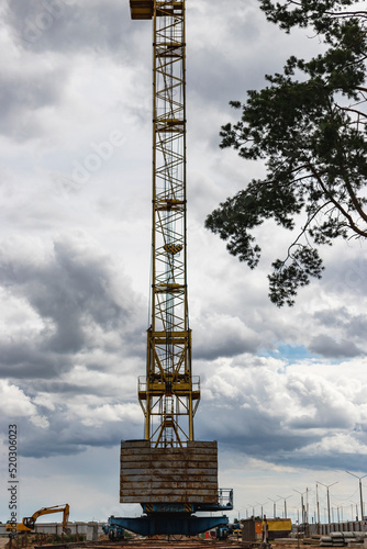 Tower crane close-up against the background of the cloudy sky. Modern building technologies.