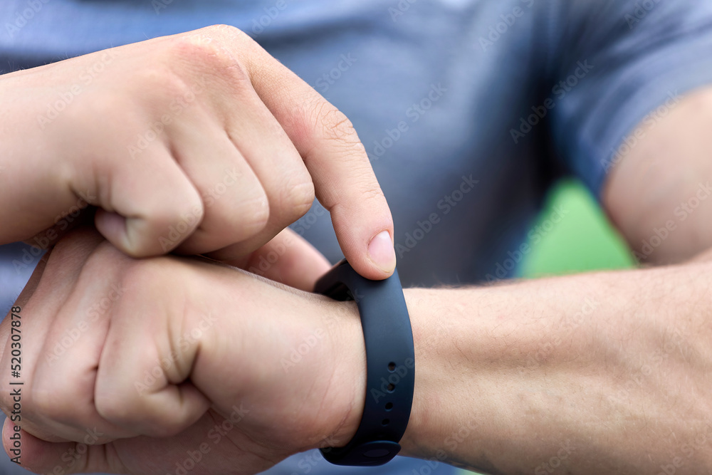 Athlete checks his performance on the fitness bracelet after training. Close-up on a man's hand modern smart watch with black strap