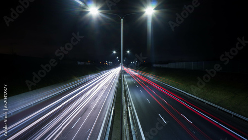 night view of the highway, visible flares of street lamps, streaks of car lights