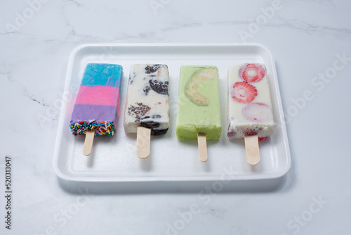 A view of several colorful paletas on a tray.