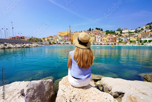 Vacation relax. Girl sitting on stone enjoying landscape of French Riviera on sunny day, Menton, France. photo