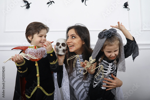 Happy family with children in costumes of witch and vampire in a house in holiday Halloween