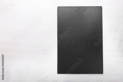 Slate board on wooden background. Cutting board. Space for text.