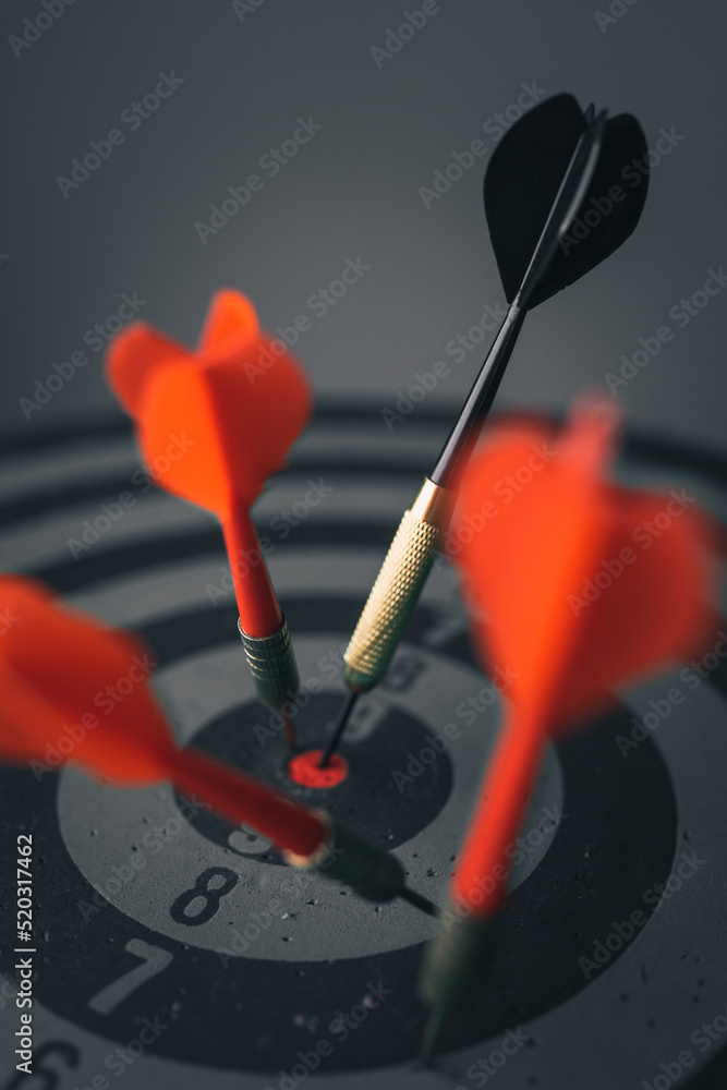 Close up shot of the dart arrow hit on bulleyes of dartboard to represent that the business reached the target of company with dark tone picture style. Target and goal as concept. Close up shot of the dart arrow hit on bulleyes of dartboard to represent that the business reached the target of company with dark tone picture style. Target and goal as concept.