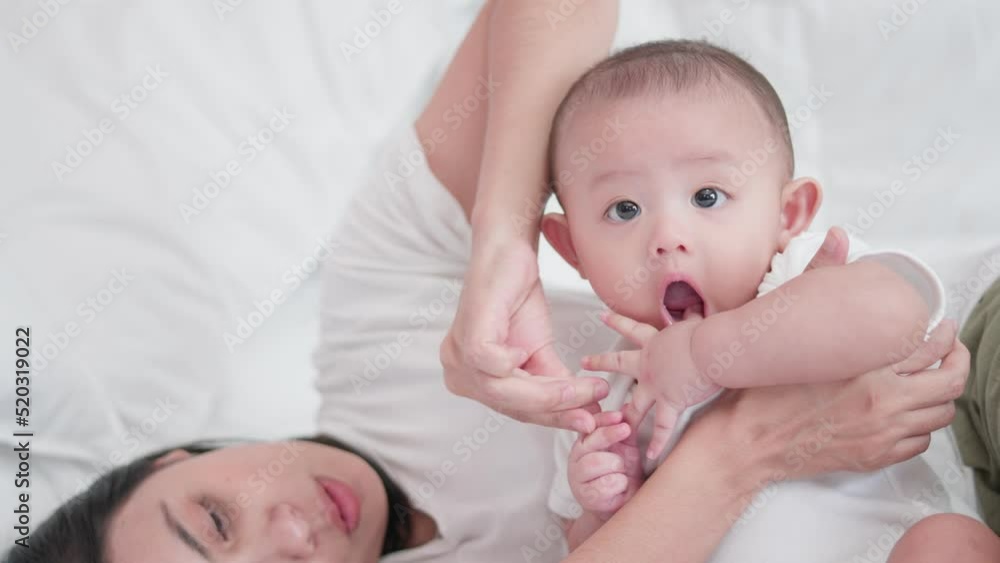 Happy family, Cute Asian newborn baby boy playing with mom takes care nearby on white bed with smile happy face. Little innocent new infant adorable child in first day of life. Mother's Day concept. Happy family, Cute Asian newborn baby boy playing with mom takes care nearby on white bed with smile happy face. Little innocent new infant adorable child in first day of life. Mother's Day concept.