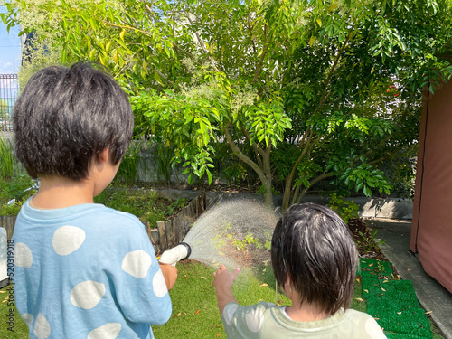 庭で水をまいて遊ぶ日本人の子供