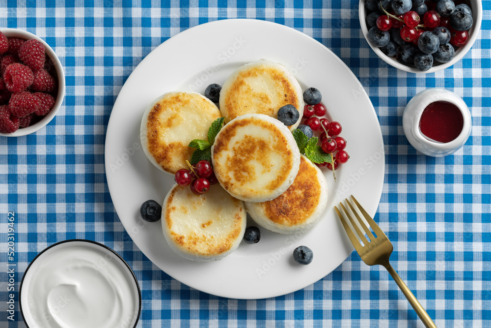 Cottage cheese pancakes on the background is blue in a cell. Syrniki with fresh blueberries.  Homemade food. Recipe. Copy space for text
