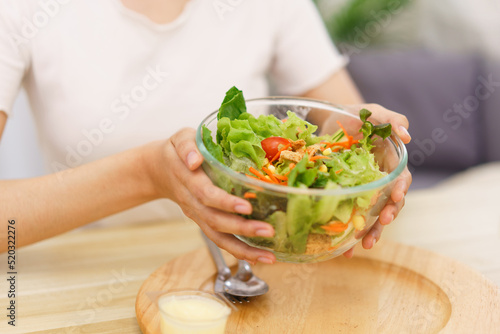 Lifestyle in living room concept, Young Asian woman smiling and holding bowl of vegetable salad