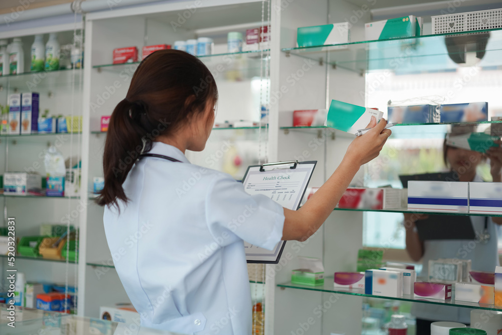 Medicine and health concept, Female pharmacist hold medicine box to checklist in paper at drugstore