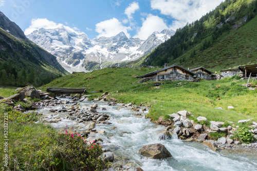 Obraz na plátně Berghütten am Wildbach mit Gletscher im Hintergrund