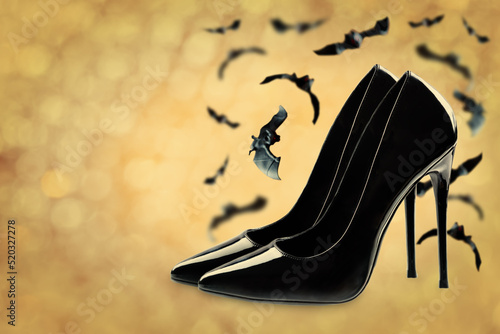 Bright black women's shoes with flying bats on a shimmering background photo